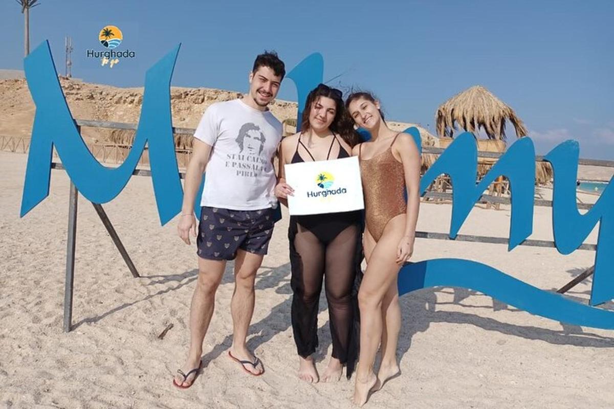 a group of three people standing on the beach