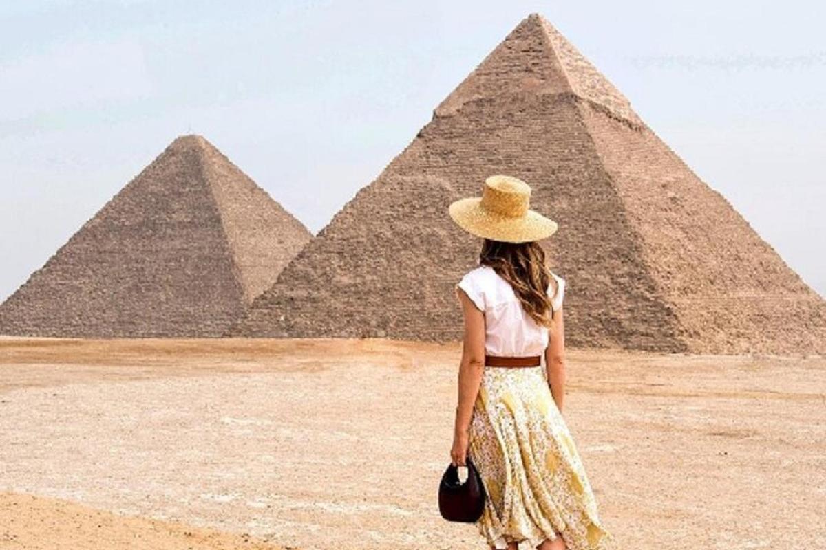 una donna con un cappello in piedi davanti alle piramidi