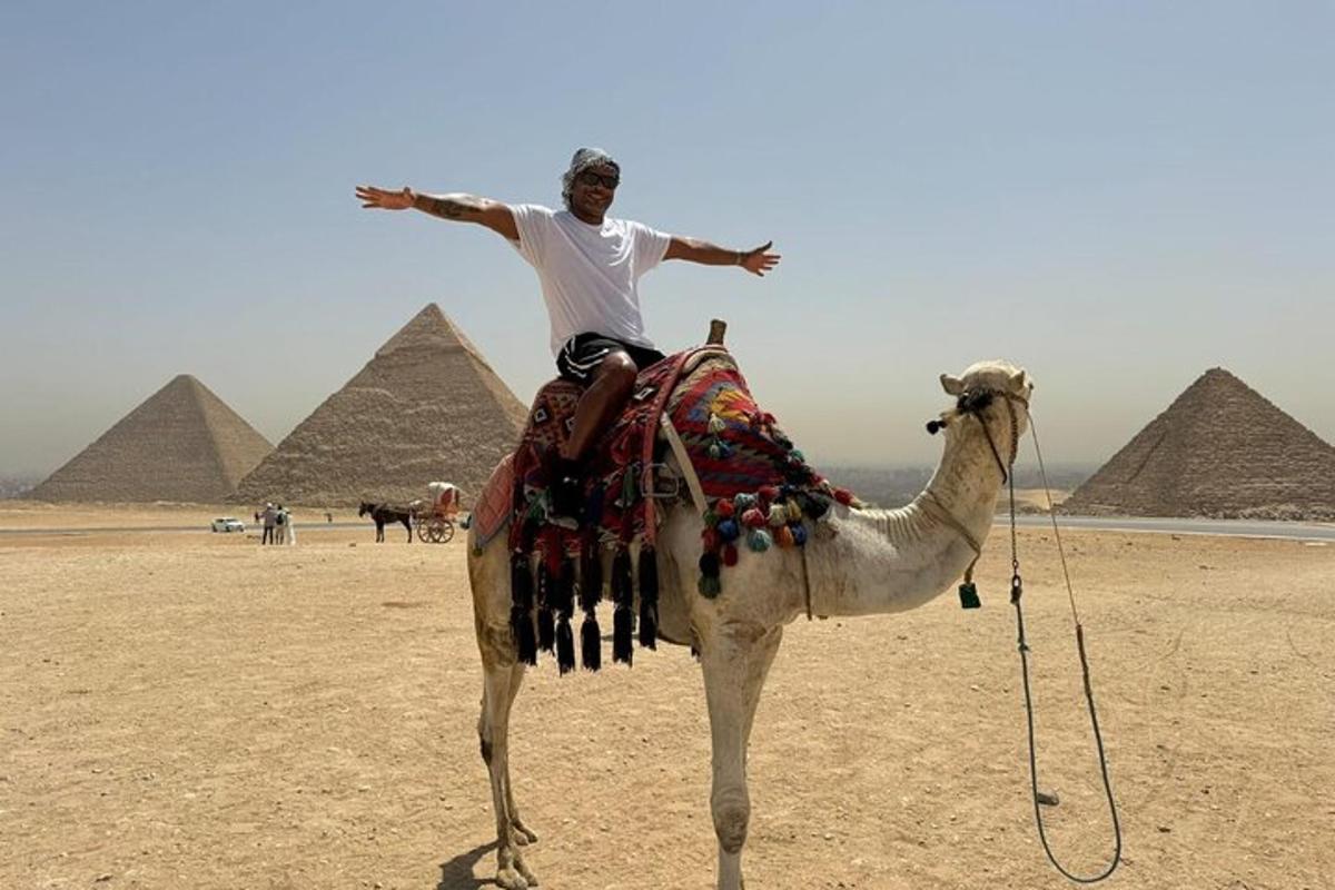 a man riding a camel in front of pyramids