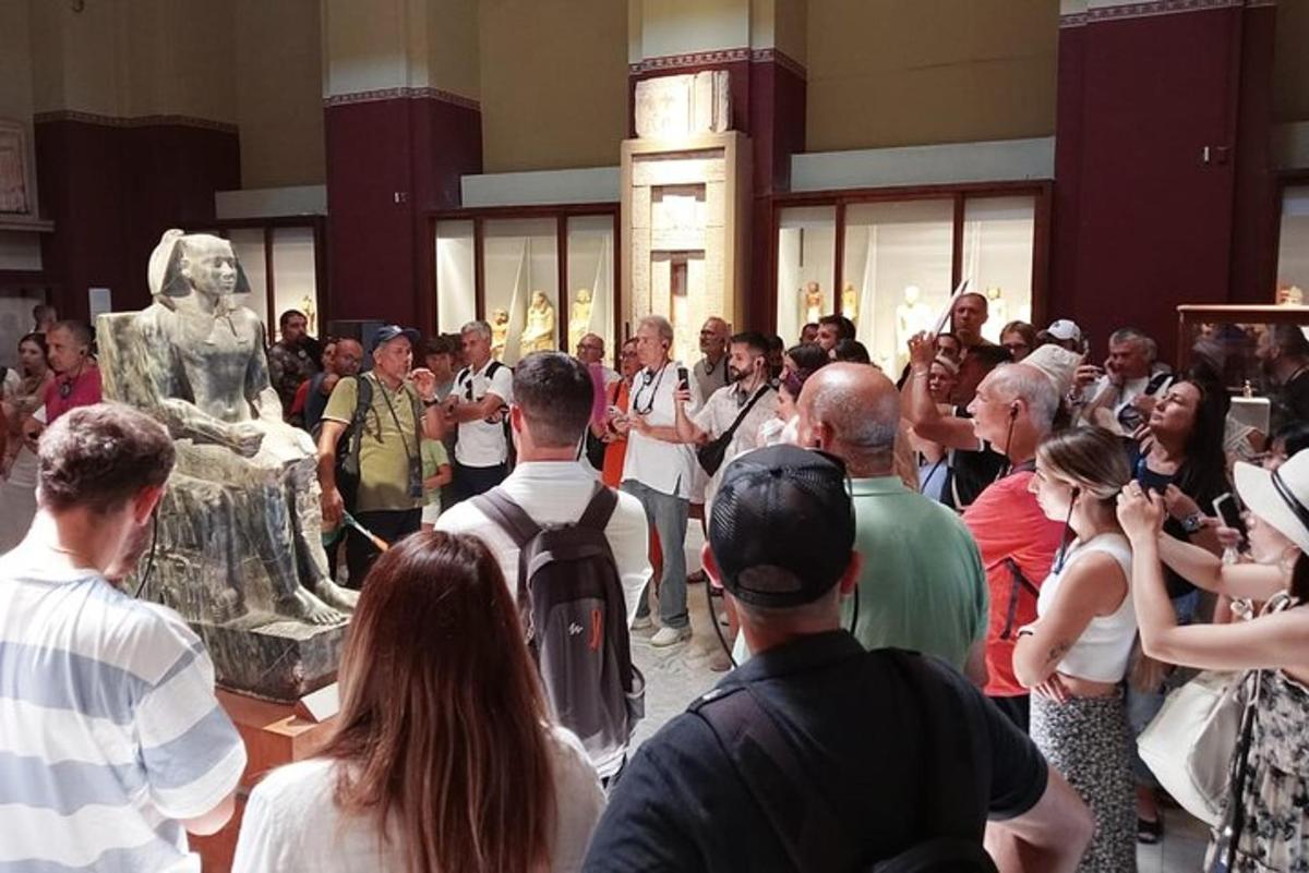 una folla di persone che guarda una statua in un museo