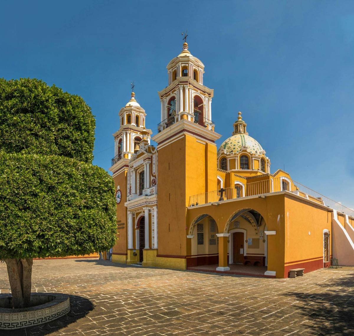 a yellow building with two towers and a tree
