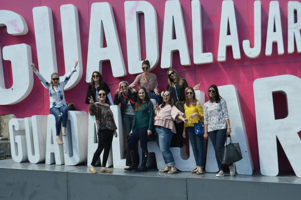 grupp naisi poseerib suure sildi ees