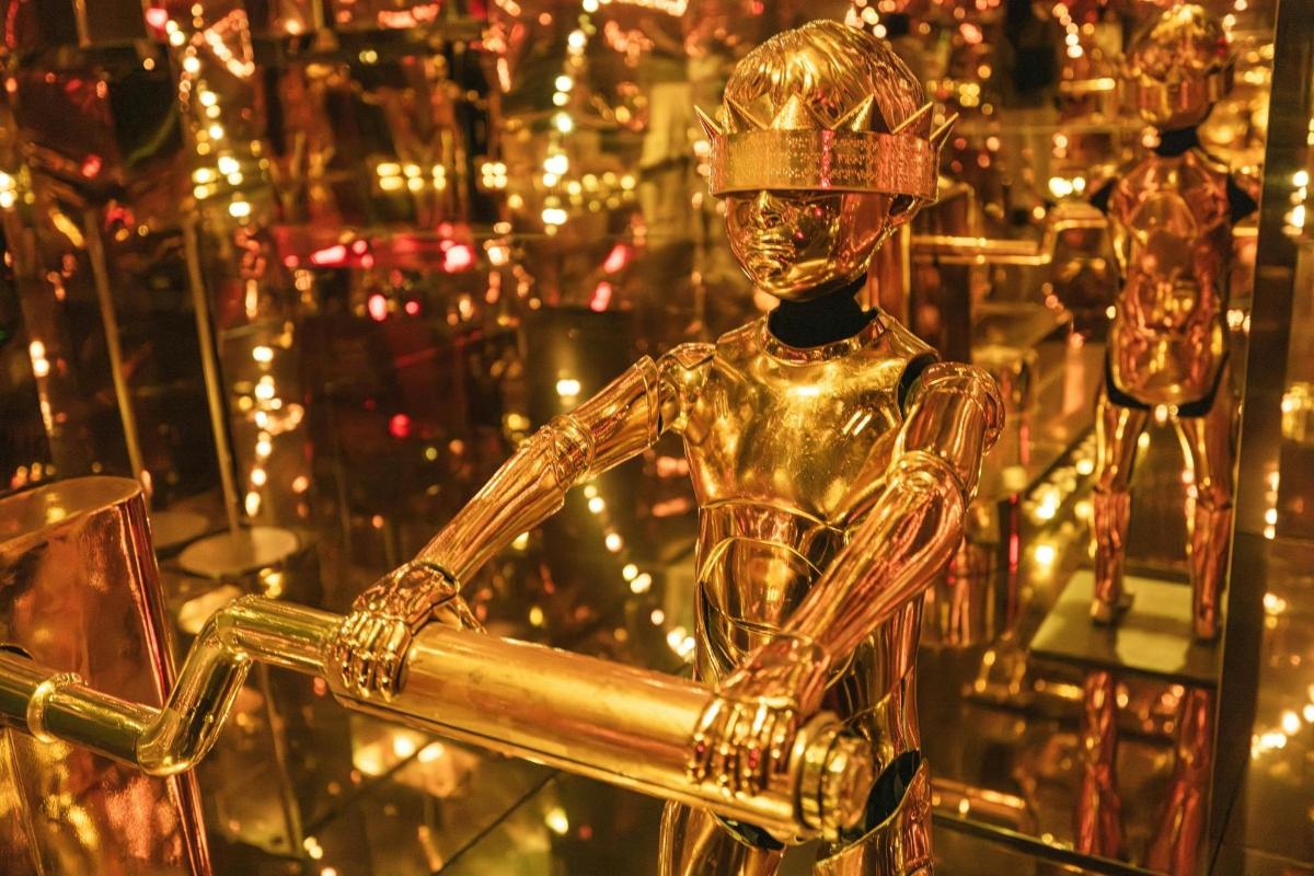 a gold mannequin in front of christmas lights