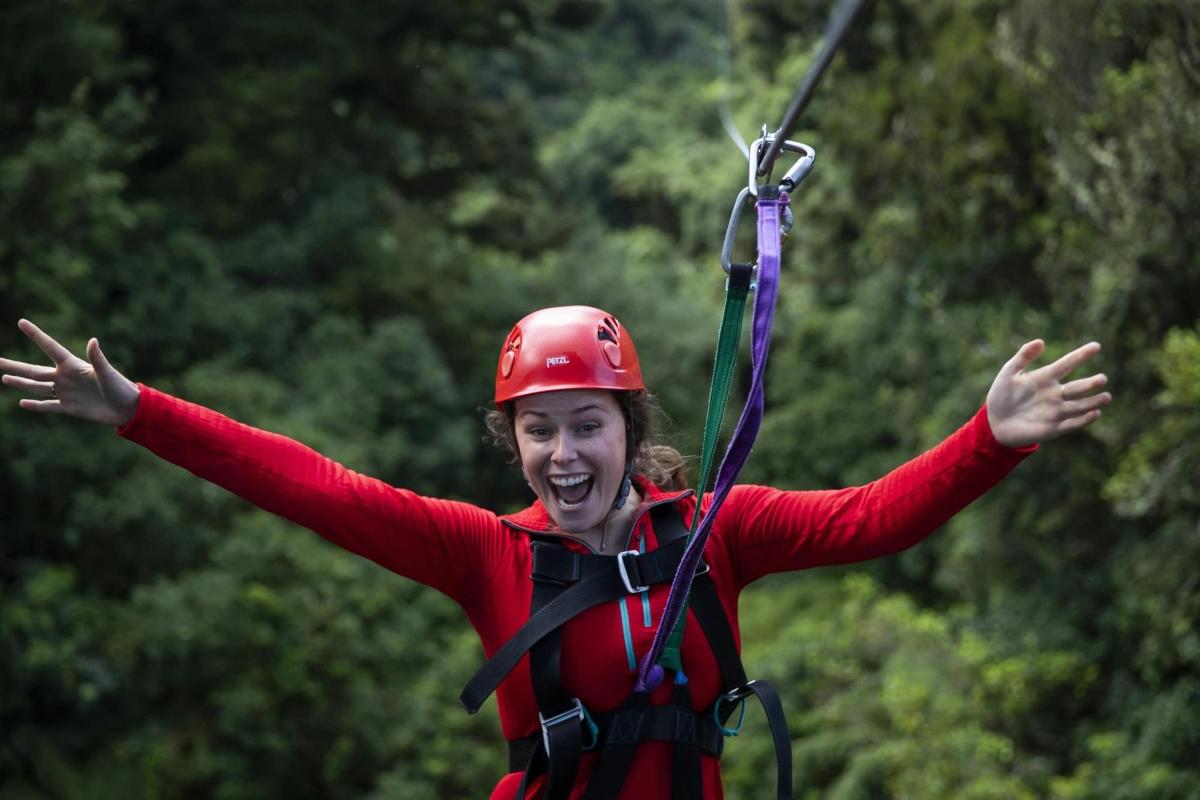 a woman in a helmet is on a zip line