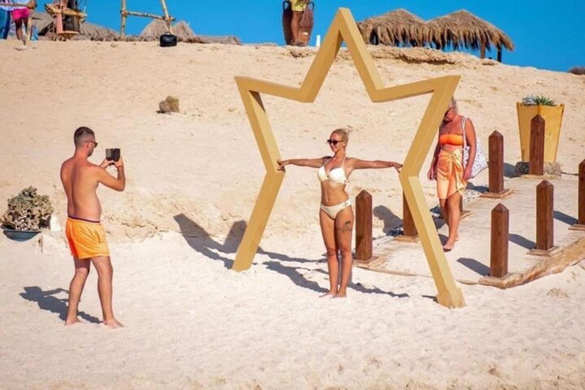 a man taking a picture of a woman in a star on the beach