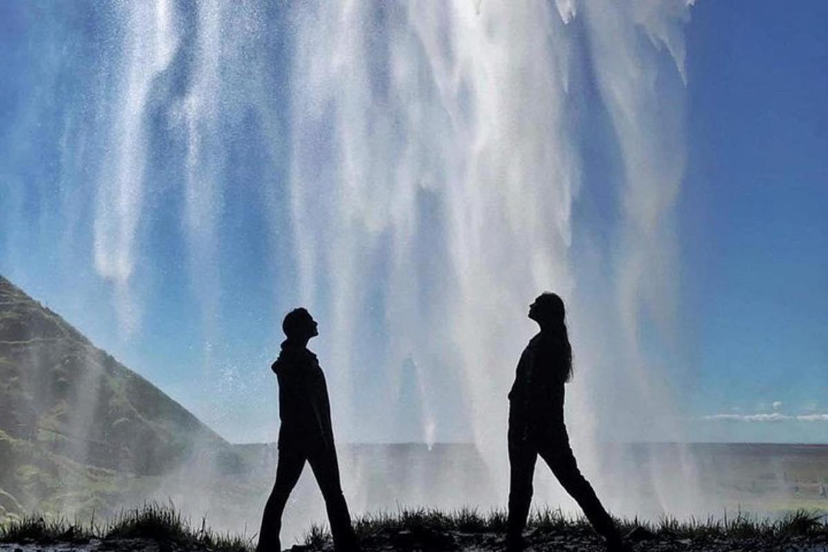 dua orang berjalan di hadapan air terjun