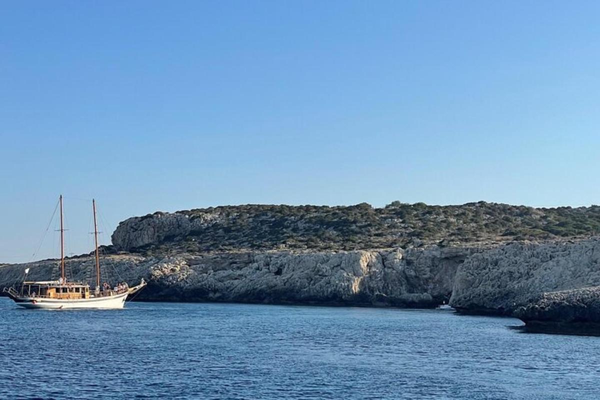 um barco parado na água ao lado de um penhasco