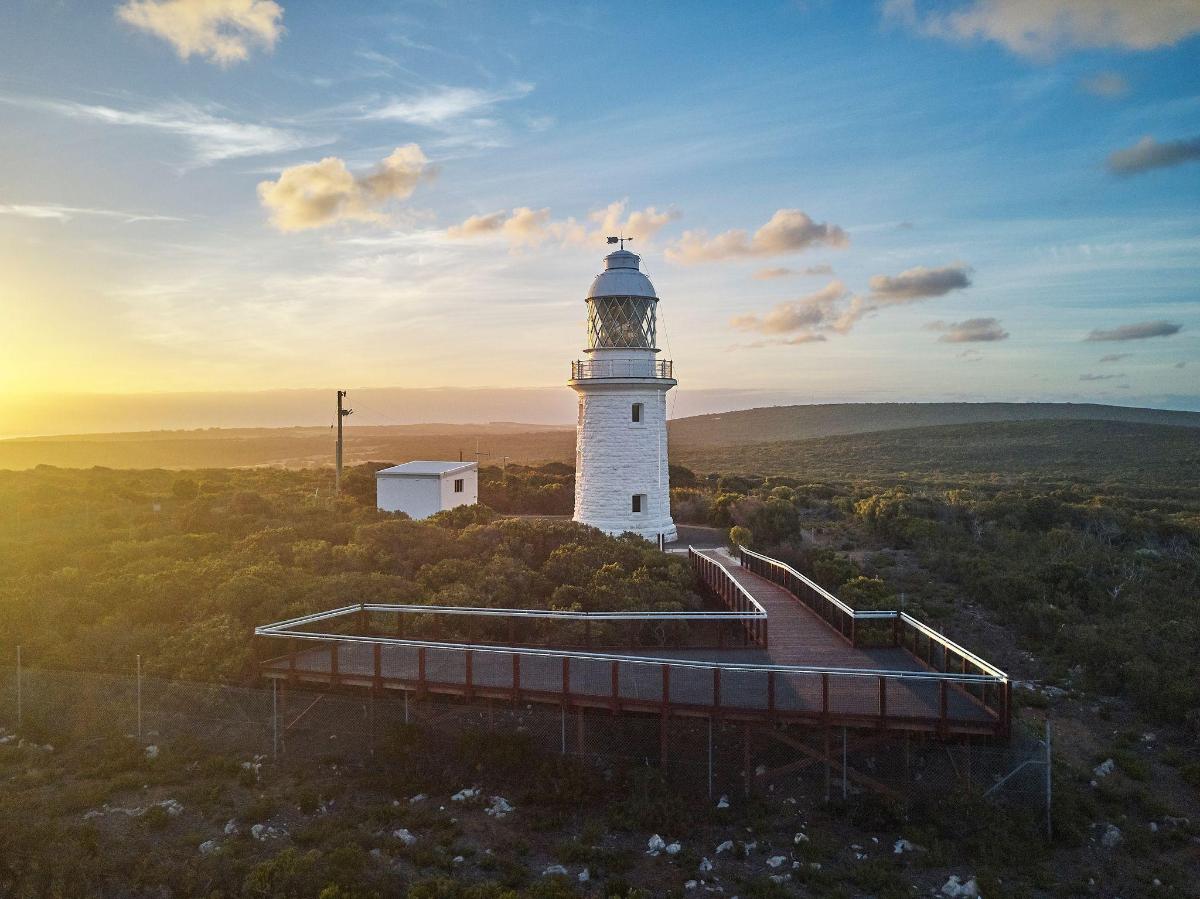 a lighthouse on a hill with the sunset in the background