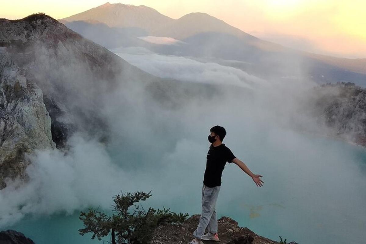 Un hombre parado en el borde de una montaña con vistas a un lago azul.
