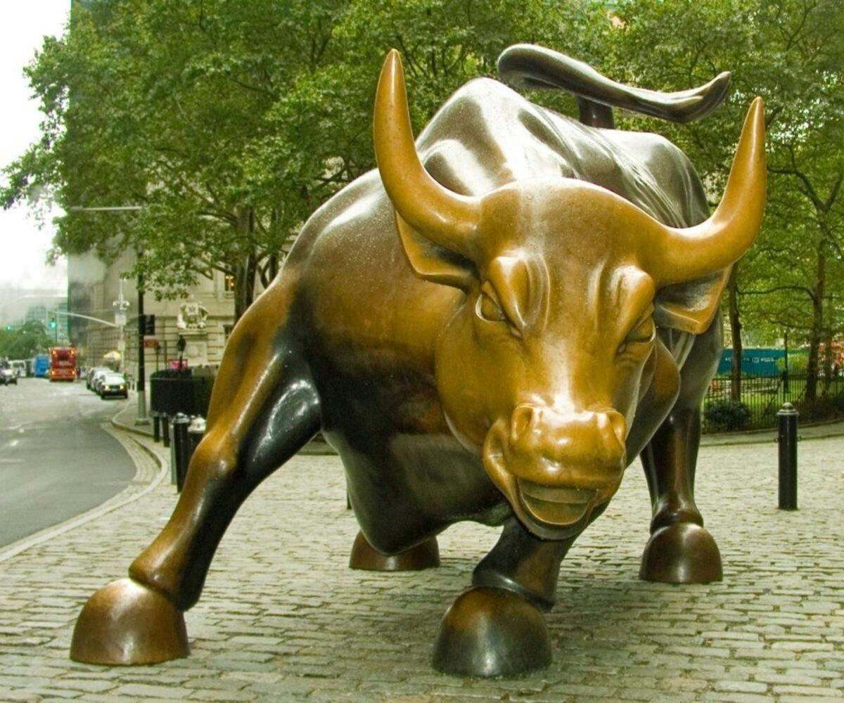a statue of a gold bull on a sidewalk