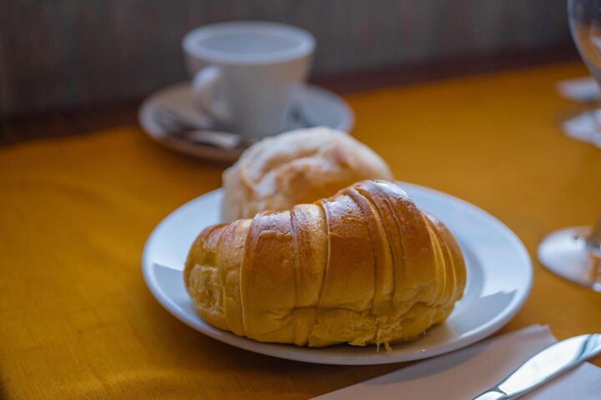 un piatto bianco con un croissant e una tazza di caffè