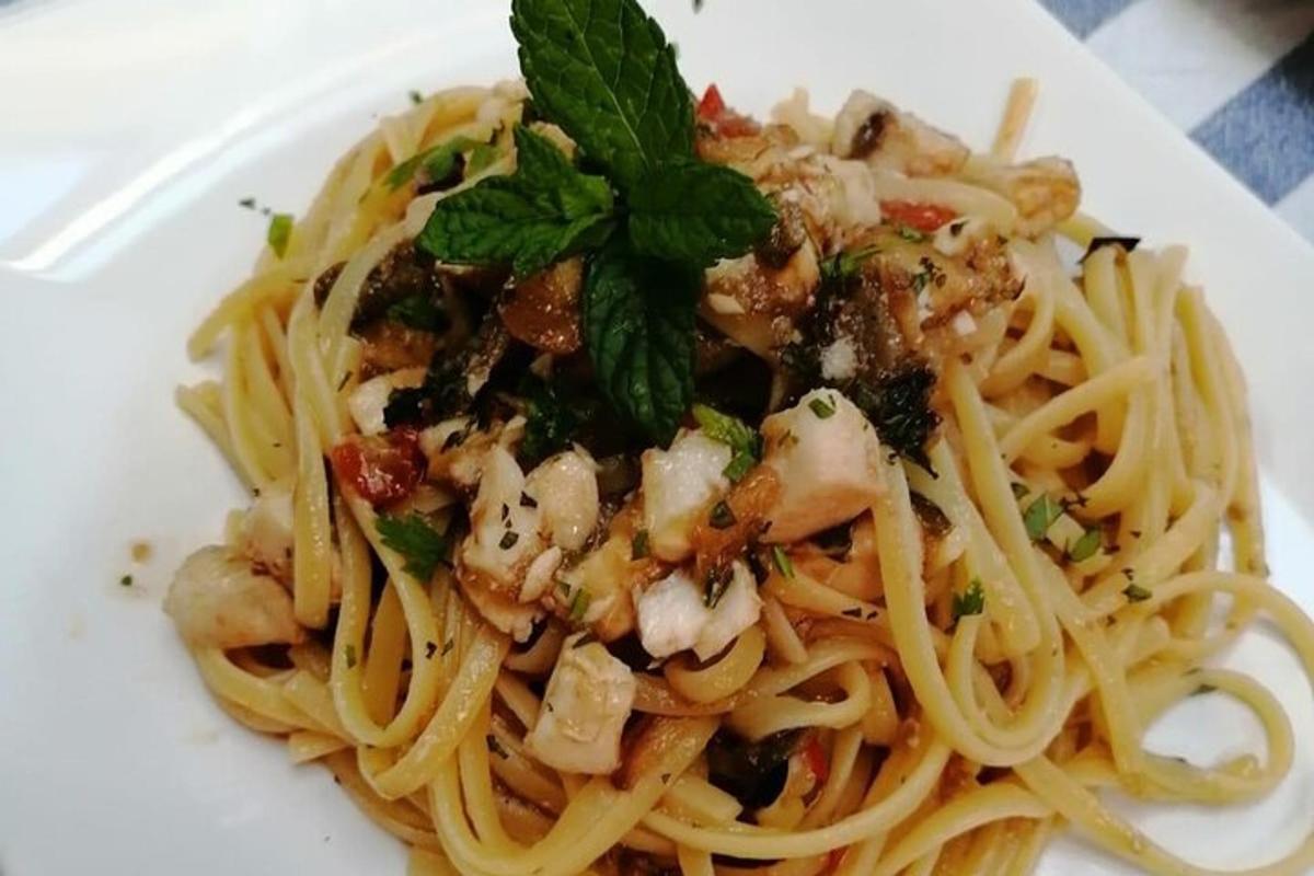 ein Teller Pasta mit Garnelen und einer grünen Garnitur