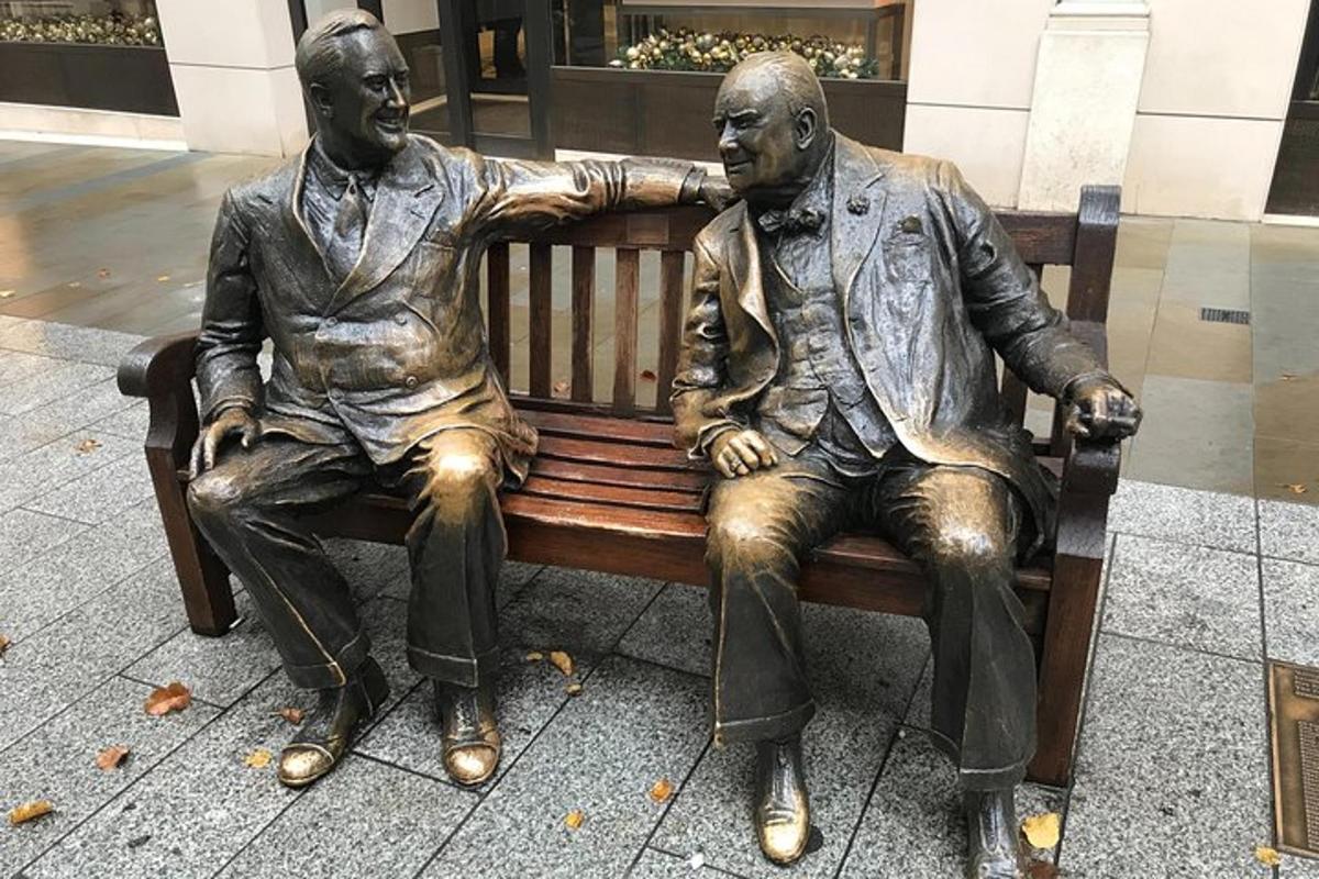 statuja, kurā attēloti divi vīrieši, kas sēž uz soliņa