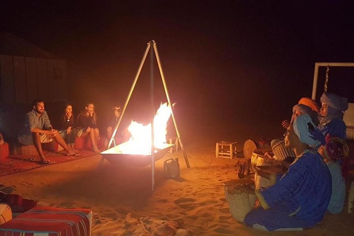 grupp inimesi istub rannas lõkke ümber