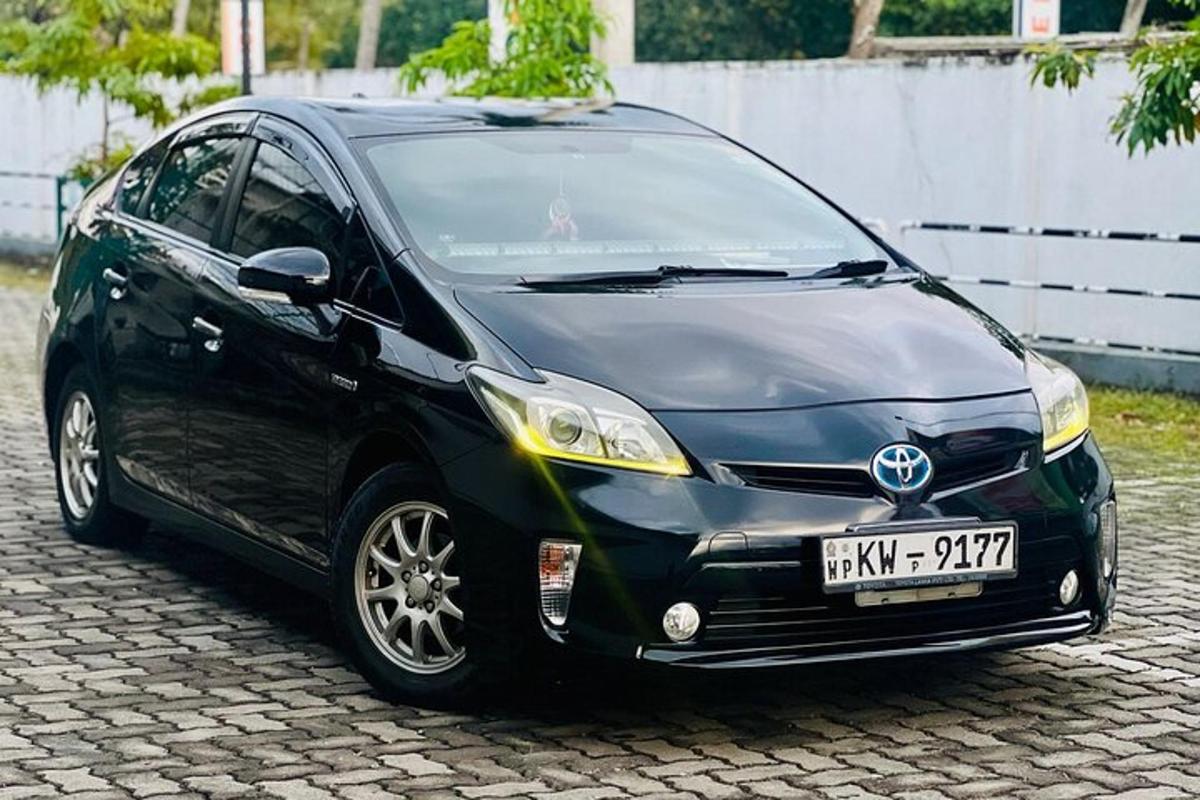 una piccola macchina nera parcheggiata su una strada di mattoni