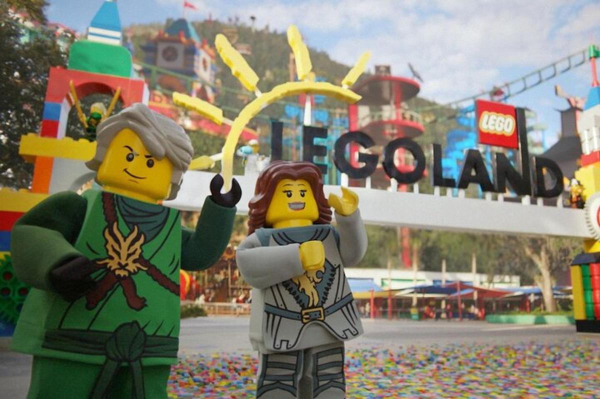 two lego people standing in front of a theme park