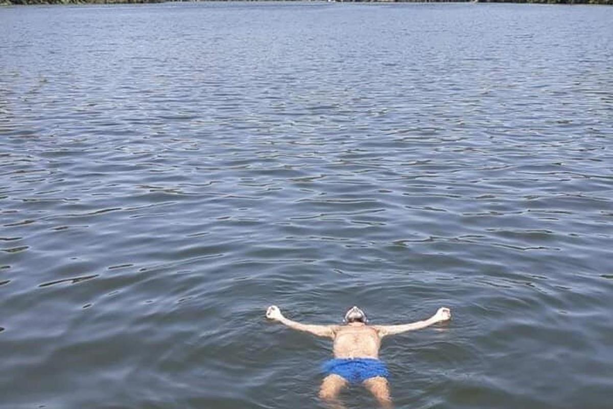 moški plava v jezeru z iztegnjenimi rokami