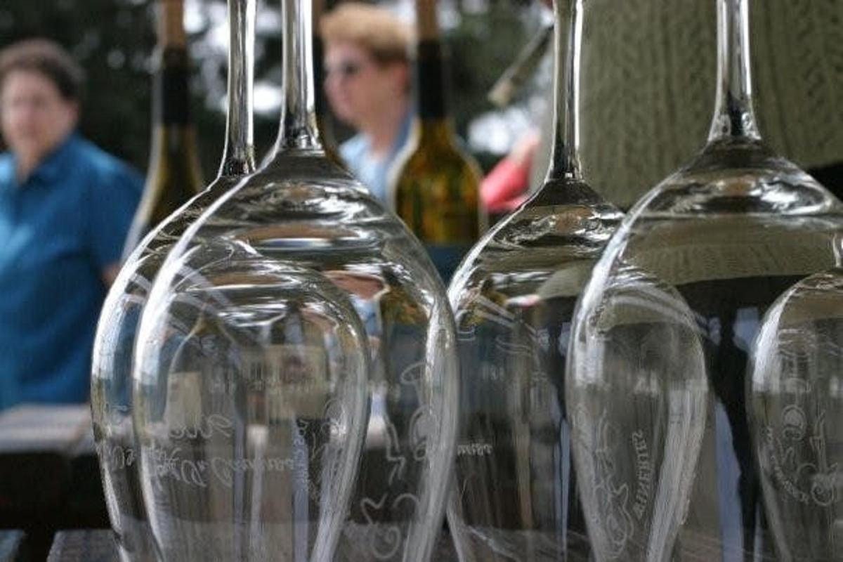 four empty wine glasses sitting on a table with wine bottles