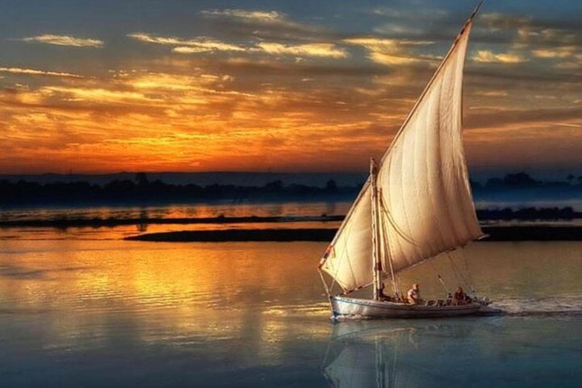 a white sail boat in the water at sunset