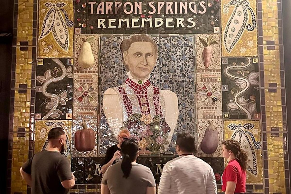 skupina lidí stojící před velkou nástěnnou malbou