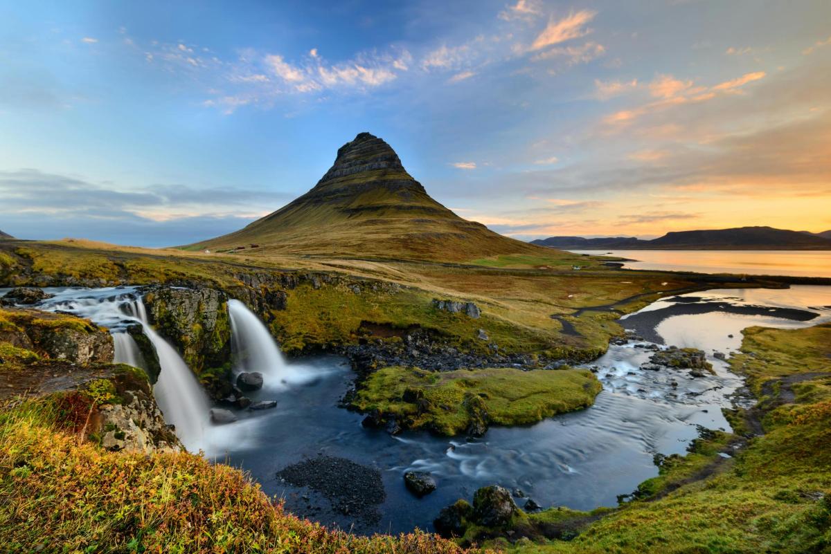 ein Wasserfall in einem Feld mit einem Berg
