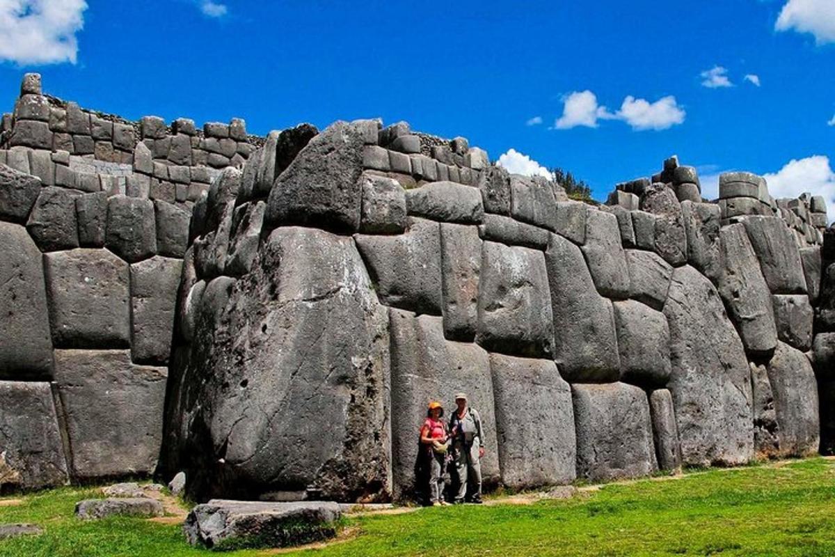 dues persones dempeus davant d'un mur de pedra