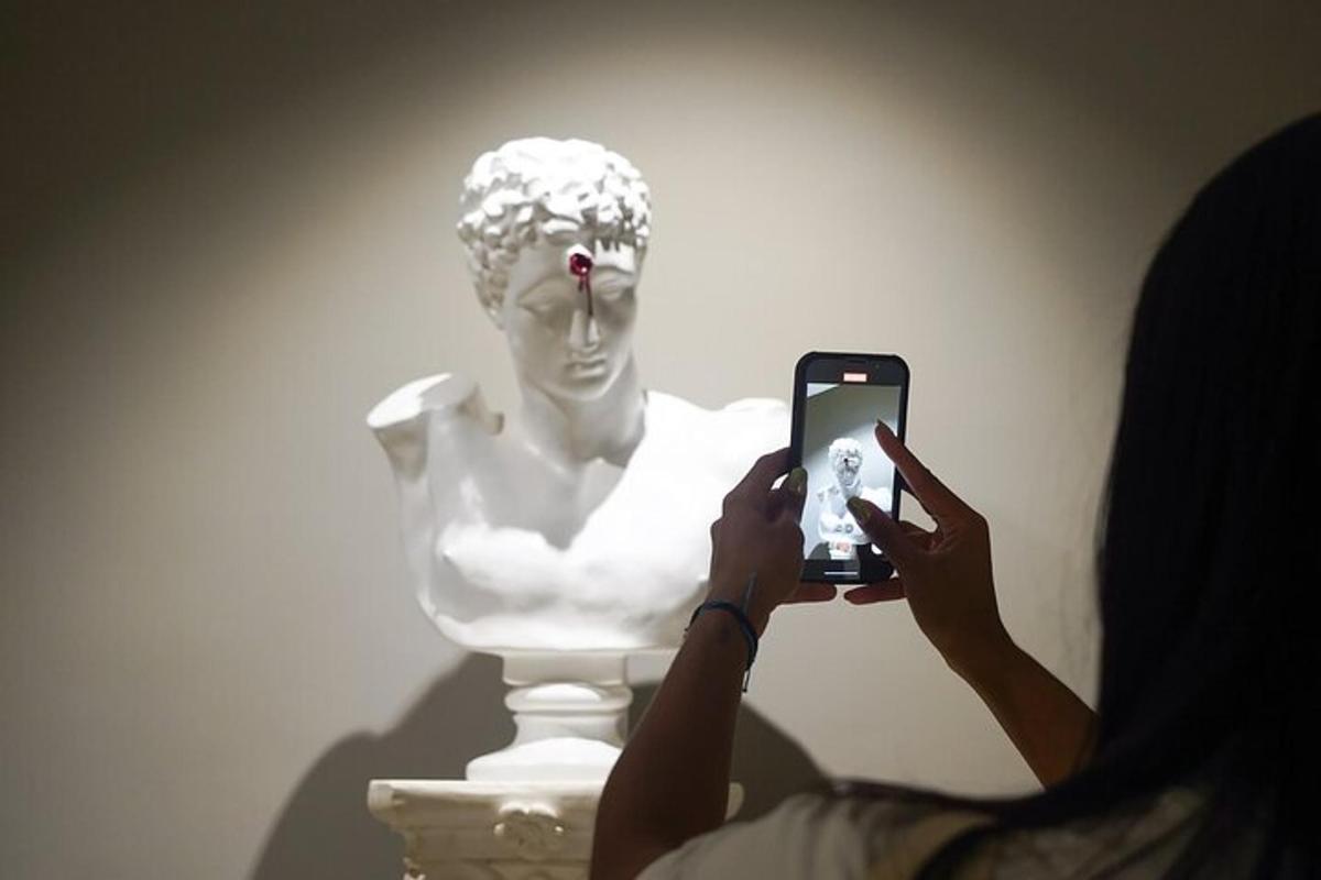 Una mujer tomando una foto de una estatua con un teléfono celular.