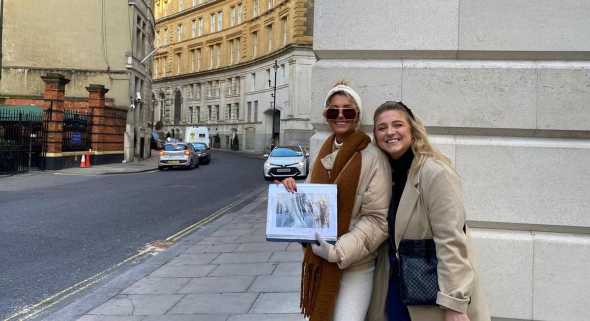 due donne in piedi su una strada che tengono in mano una foto