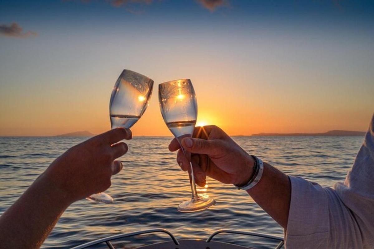 Dos personas sosteniendo copas de vino frente al océano.