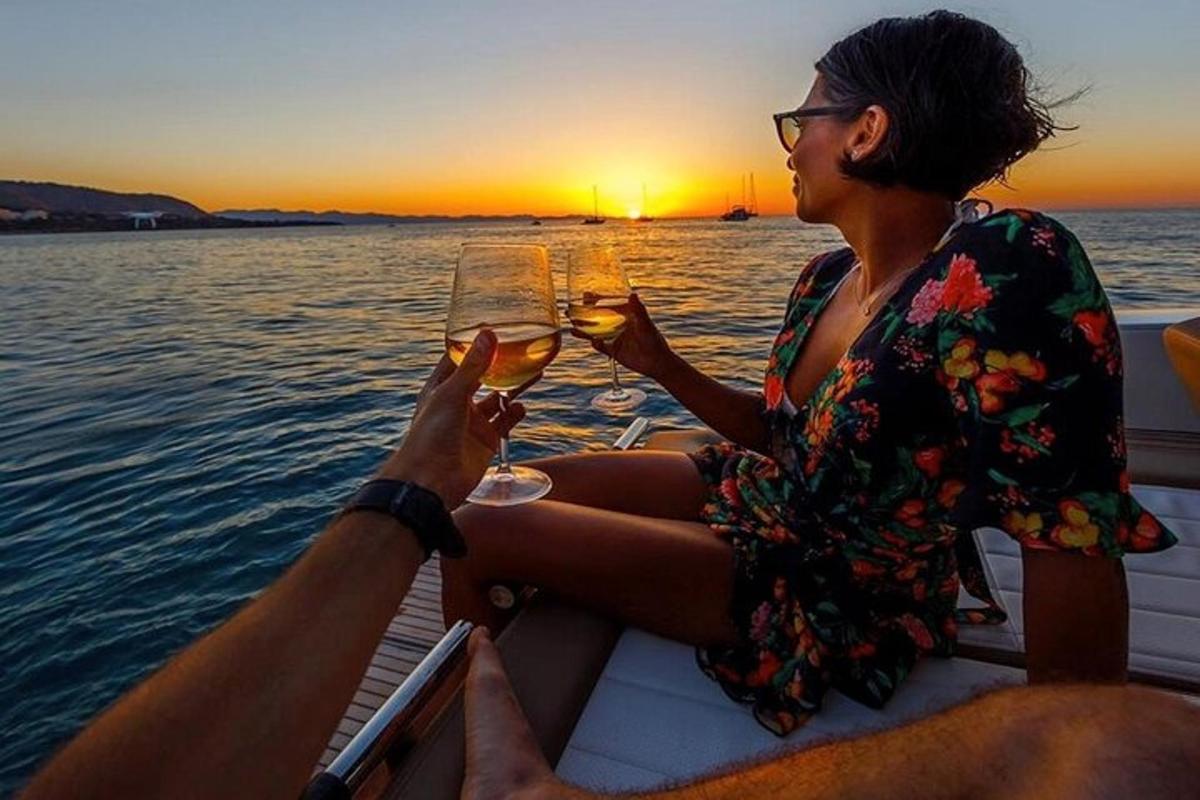 una donna e un uomo seduti su una barca con bicchieri di vino