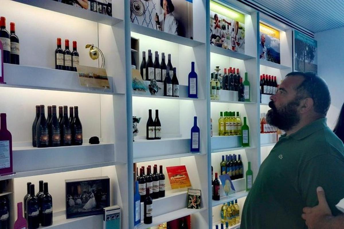 a man standing in a store with bottles of wine