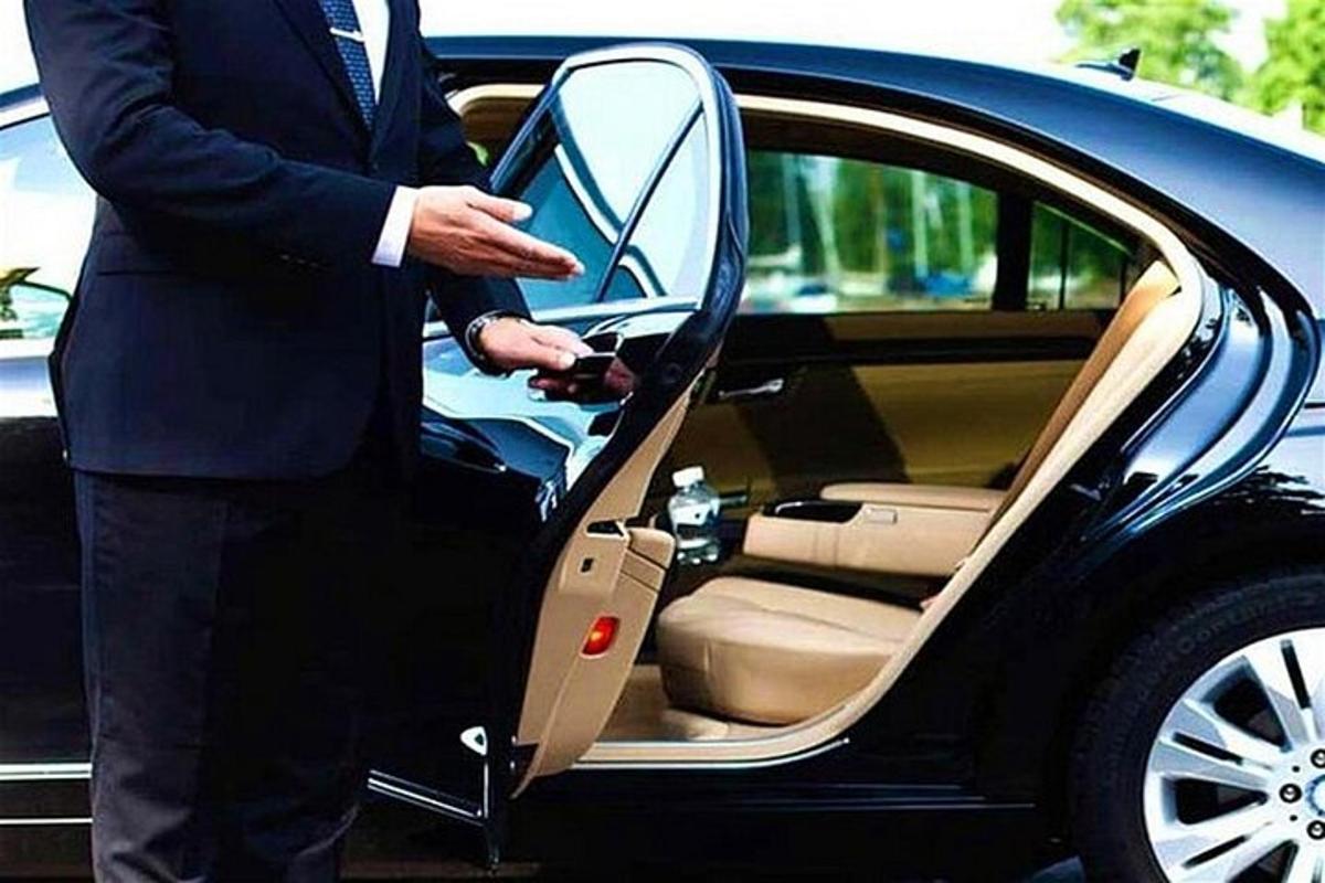 Un hombre con traje abriendo la puerta de un coche.