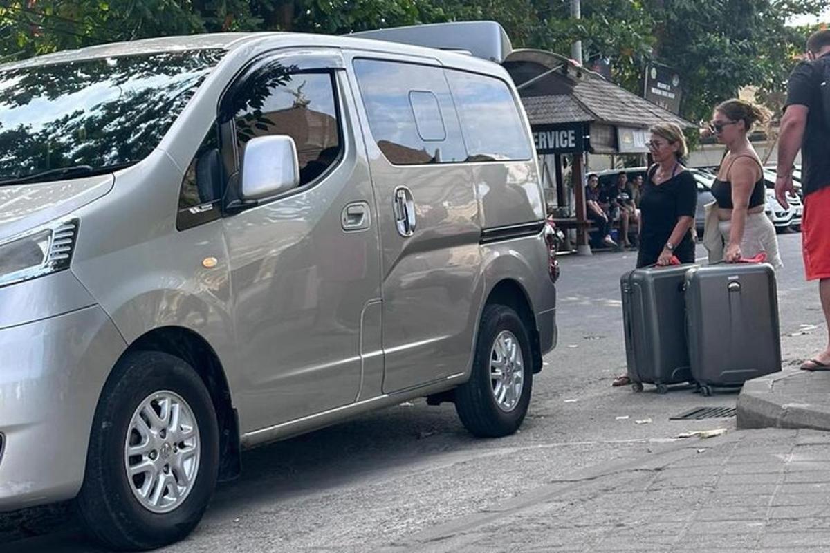 một người phụ nữ đứng cạnh một chiếc xe tải màu bạc với một chiếc vali