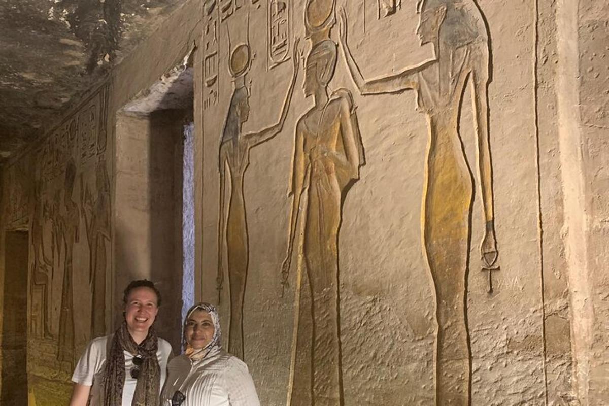 Dos personas de pie frente a una pared con una pintura.