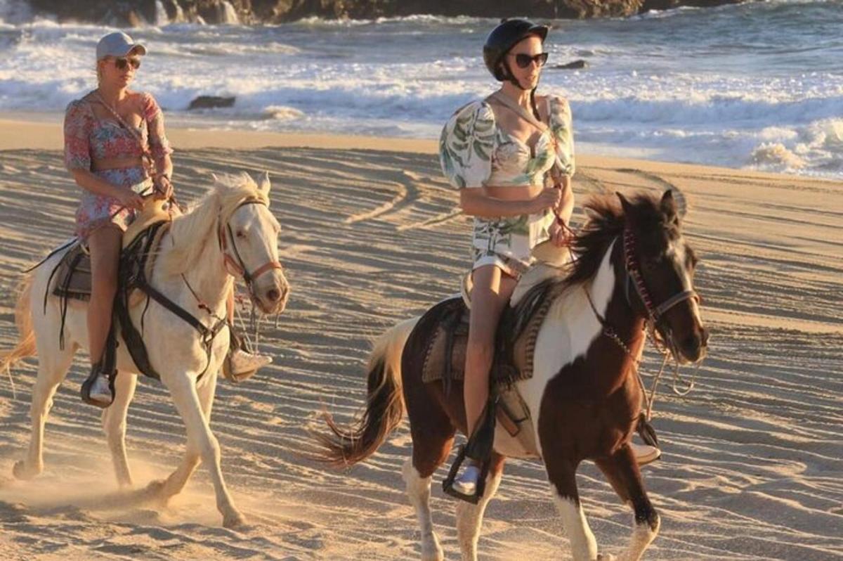 due donne stanno cavalcando sulla spiaggia