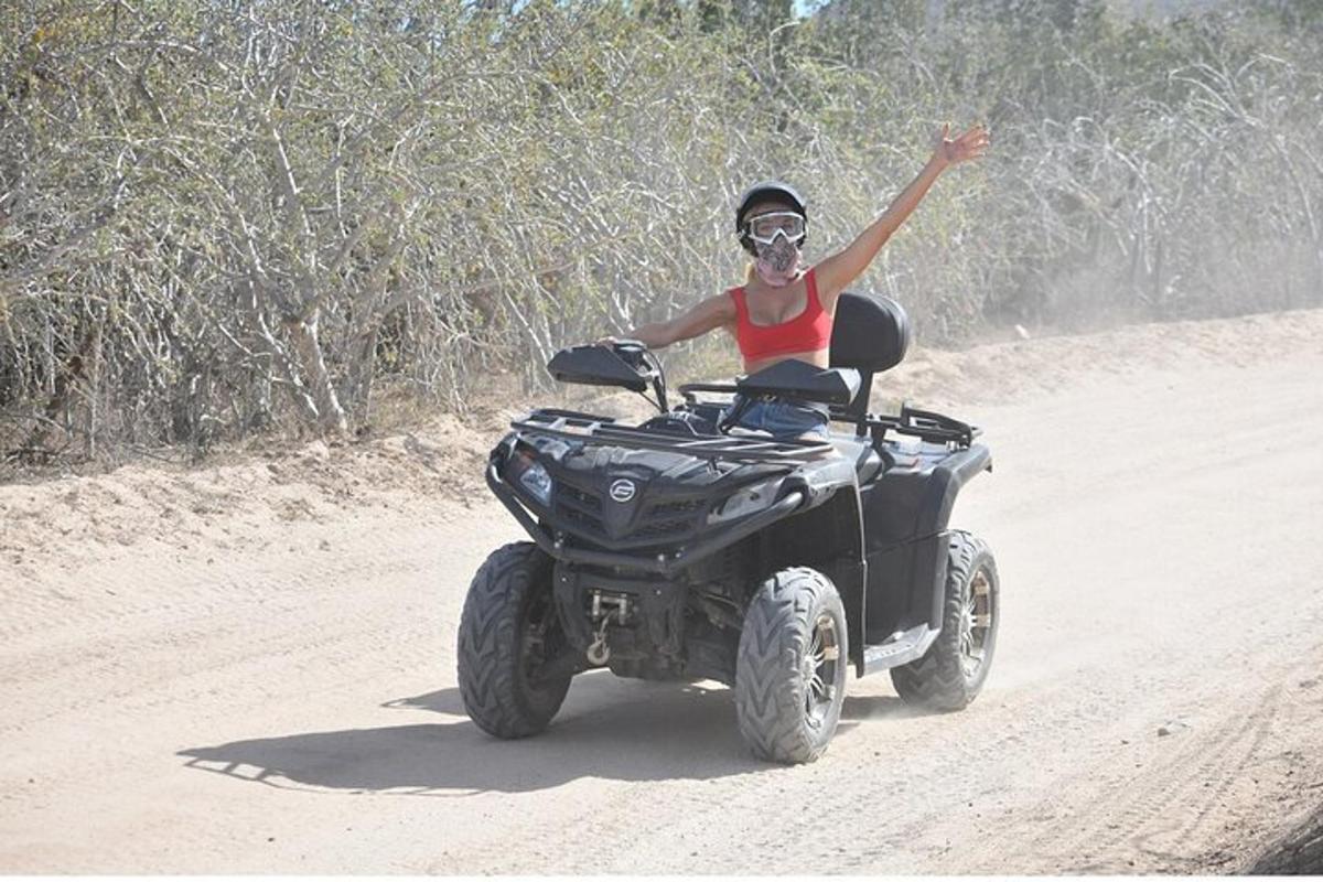 una donna in sella a un quad su una strada sterrata