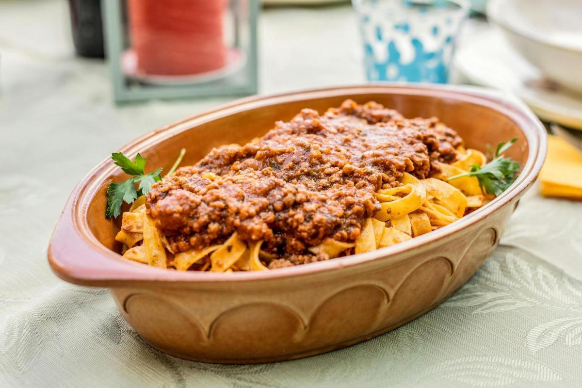 Un plato de pasta con carne y salsa sobre una mesa.