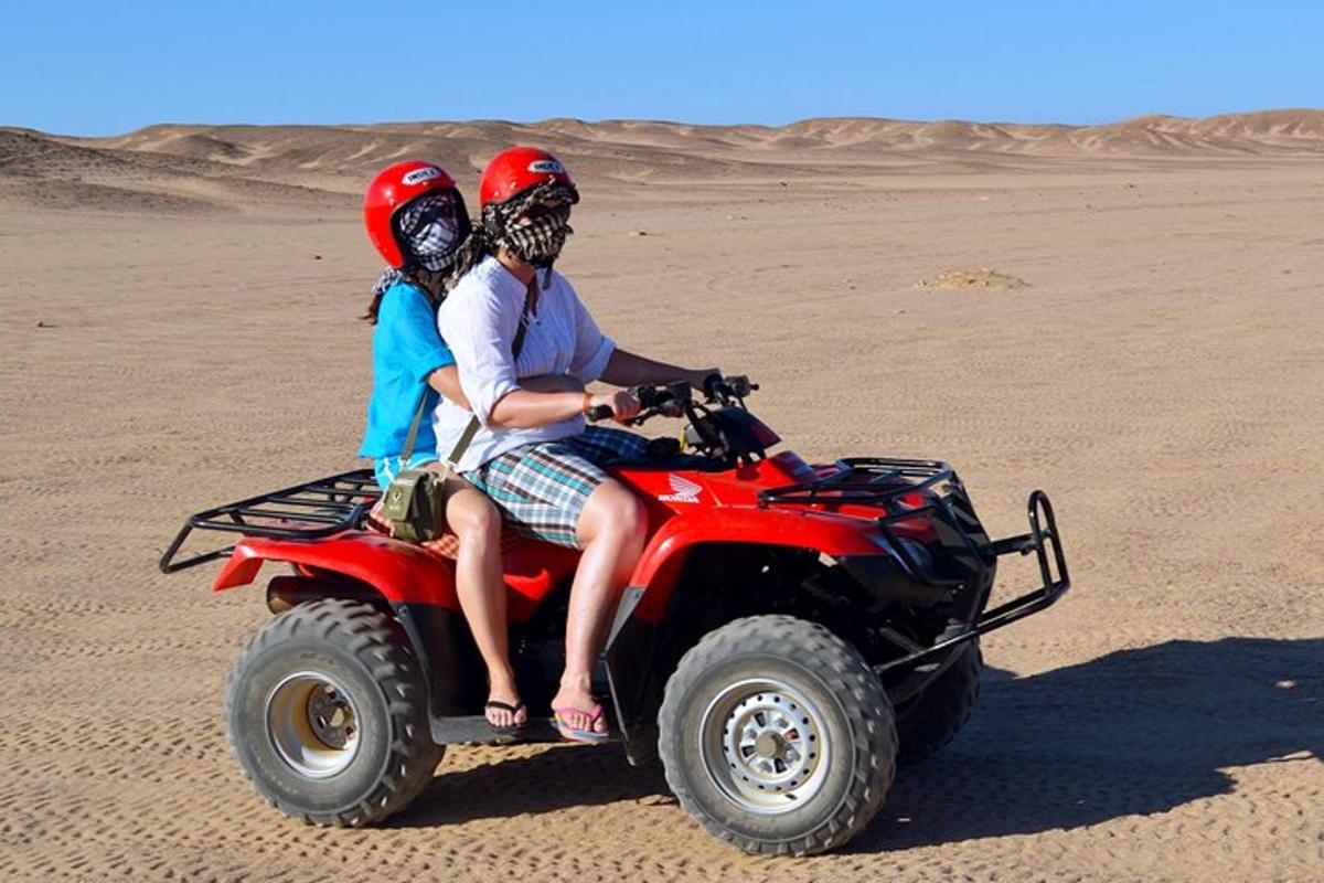 due persone a bordo di un veicolo a quattro ruote nel deserto