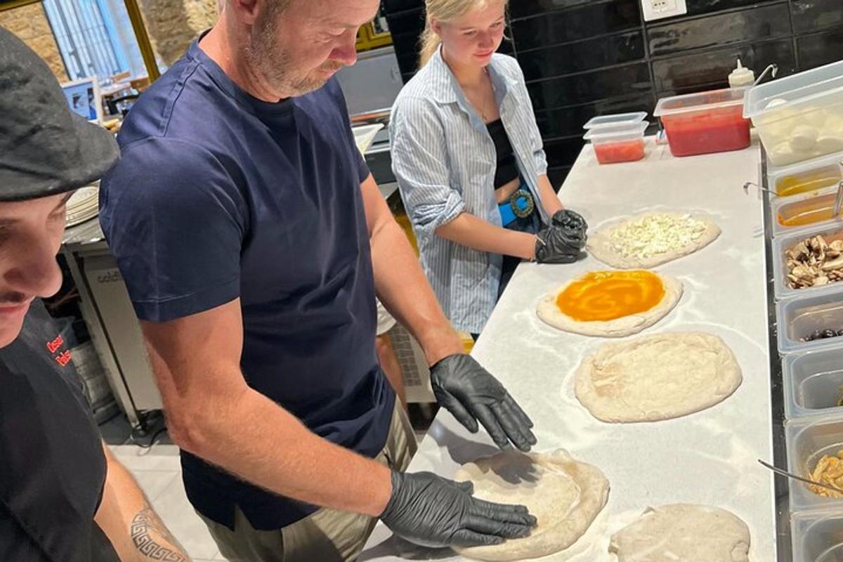 Un hombre y una mujer haciendo pizzas en una cocina.