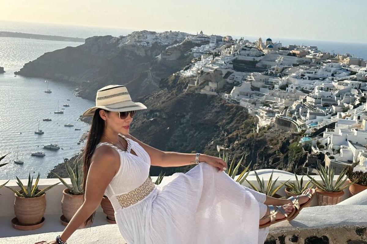 una donna con un abito bianco e un cappello seduta su una sporgenza