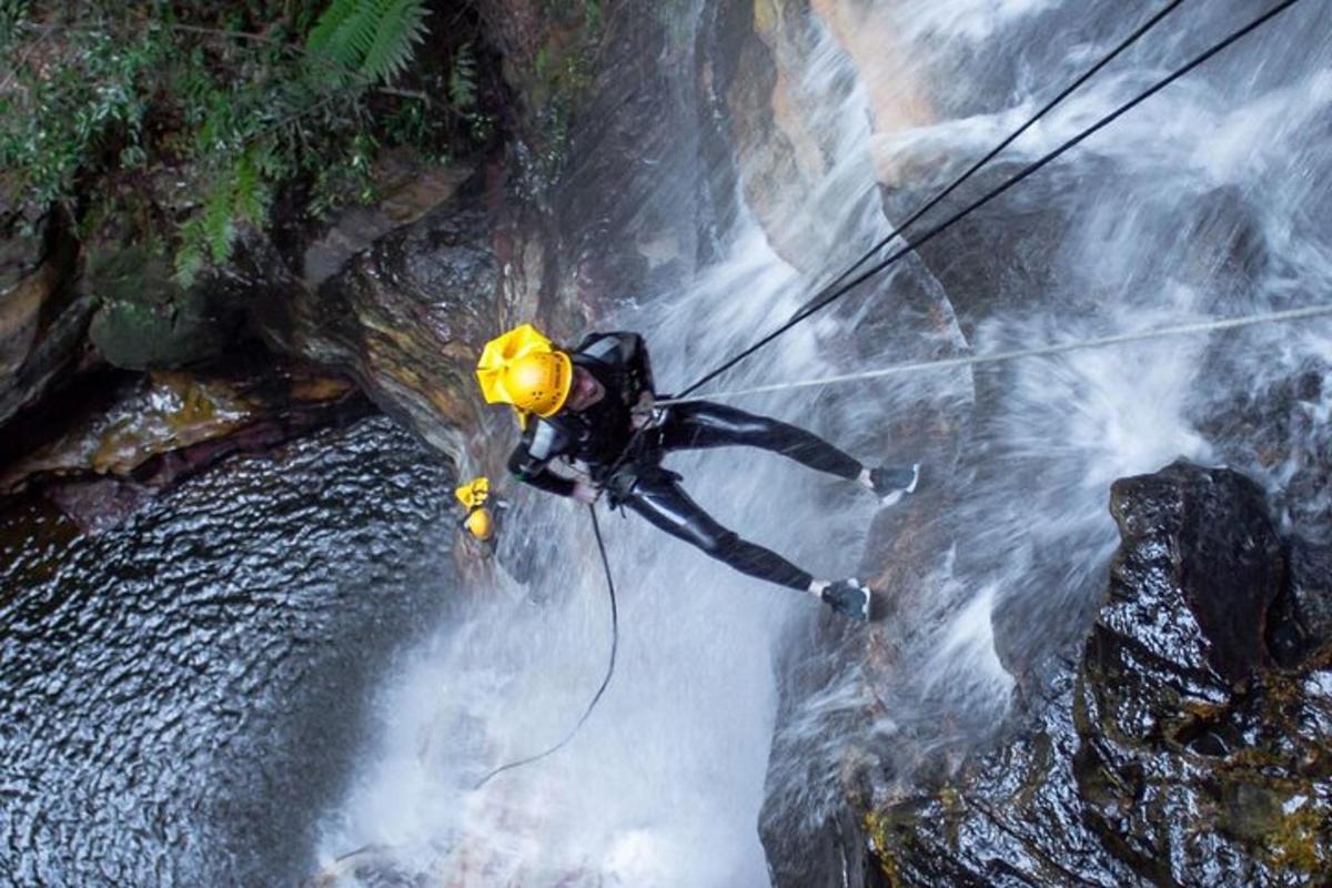 a man is rappelling over a waterfall in a river