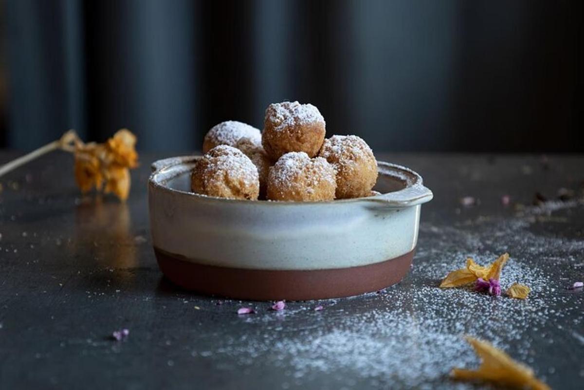 eine Schüssel mit überzuckerten Donuts auf einem Tisch