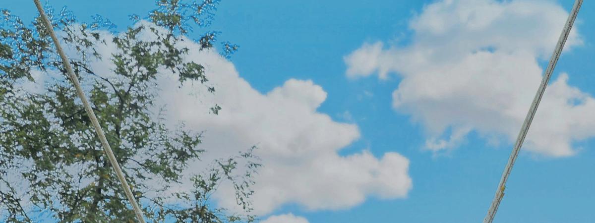 ein blauer Himmel mit einigen Wolken und einem Baum