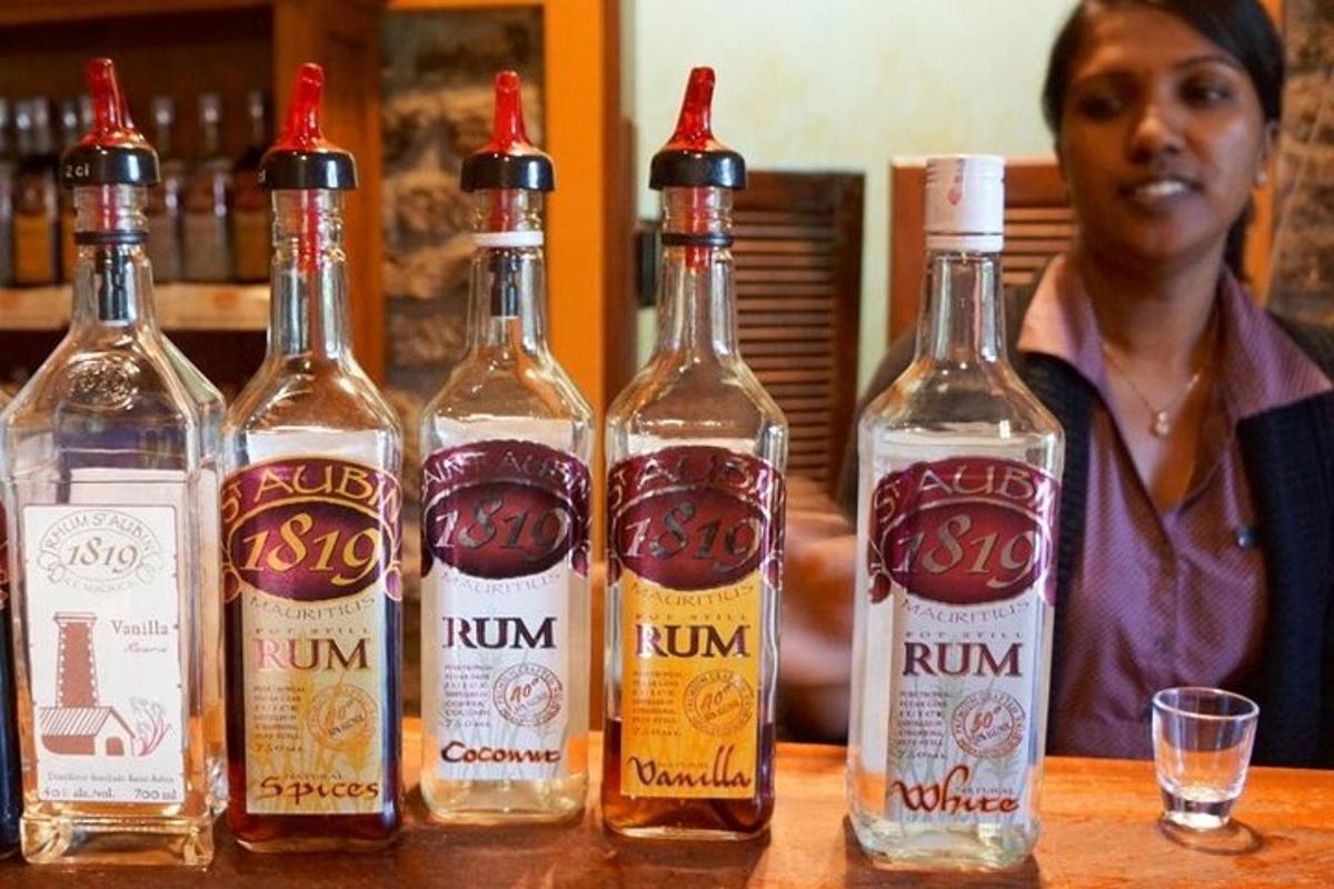 seorang wanita berdiri di belakang meja dengan empat botol alkohol