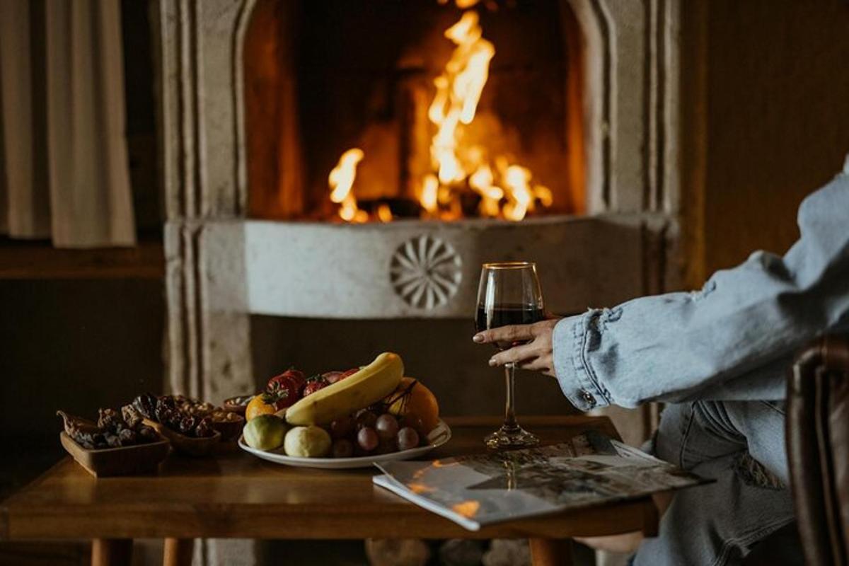 a person holding a glass of wine in front of a fireplace