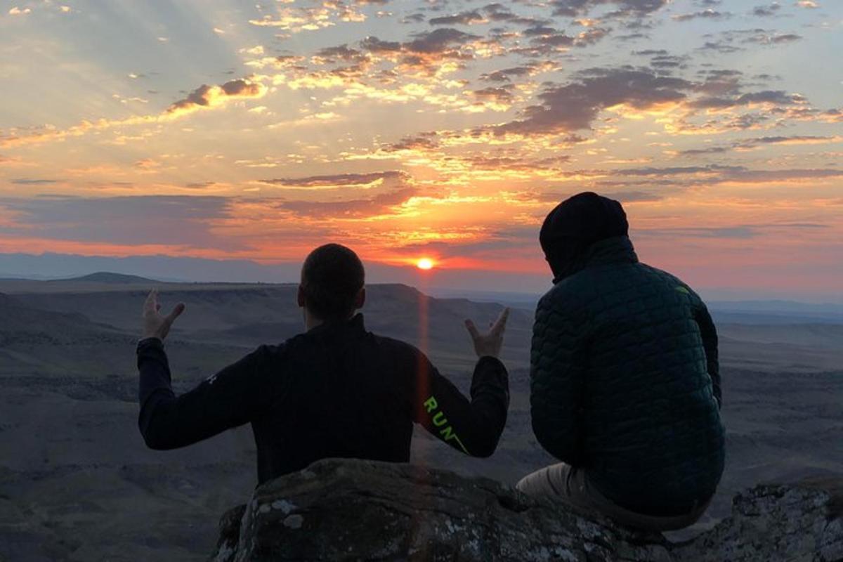 due persone sedute su una roccia che guardano il tramonto