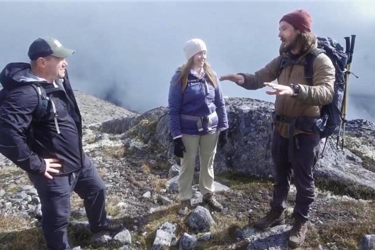 a group of three people standing on top of a mountain