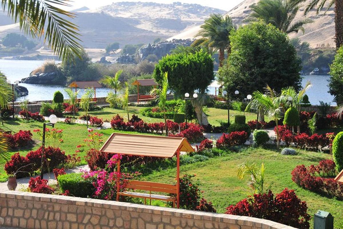 Un parque con un banco y flores y un cuerpo de agua.