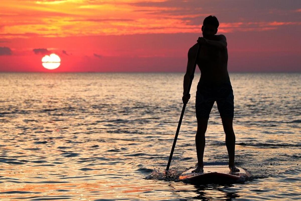 Muž stojí na paddleboardu v oceánu