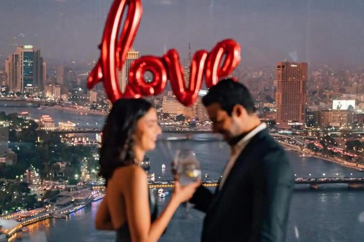 a man and a woman standing in front of a sign with the word love